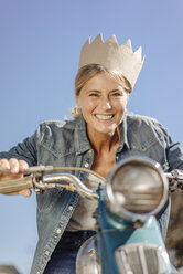 Lächelnde Frau auf Oldtimer-Motorrad, die eine Krone trägt - JOSF00832