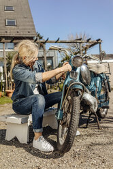 Frau beim Reinigen eines alten Motorrads - JOSF00835
