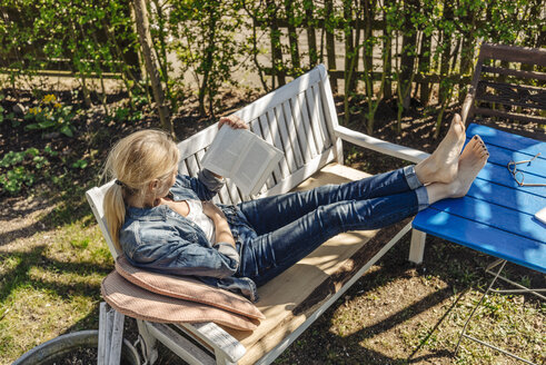 Frau liest Buch auf Gartenbank - JOSF00840