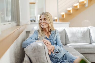 Smiling woman at home sitting on couch - JOSF00844