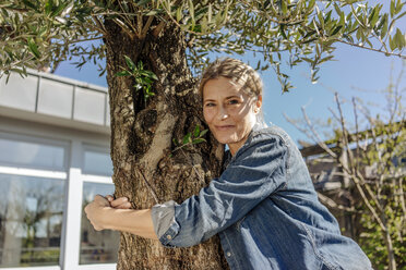 Woman in garden hugging a tree - JOSF00845