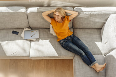 Smiling woman at home lying on couch - JOSF00851