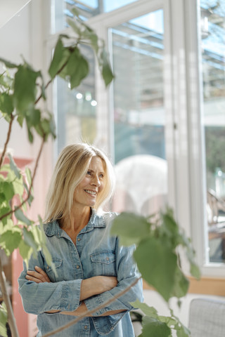 Lächelnde Frau zu Hause am Fenster, lizenzfreies Stockfoto