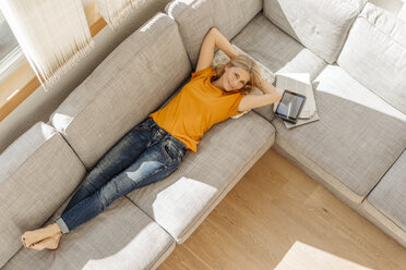 Smiling woman at home lying on couch - JOSF00861
