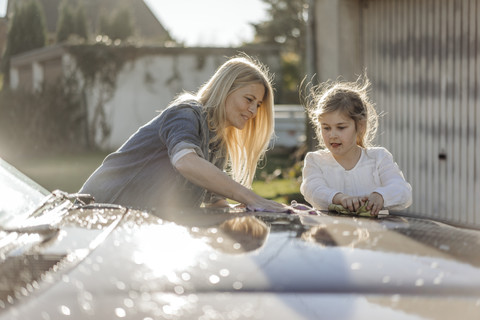 Reife Frau und Mädchen reinigen gemeinsam Auto, lizenzfreies Stockfoto