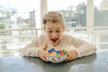 Aufgeregtes Mädchen mit Schokoladen-Ostereiern auf dem Tisch - JOSF00881