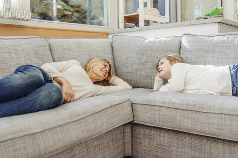 Reife Frau und Mädchen zu Hause auf der Couch liegend, lizenzfreies Stockfoto