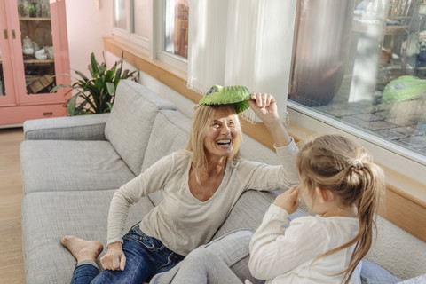 Playful mature woman and girl at home on couch stock photo