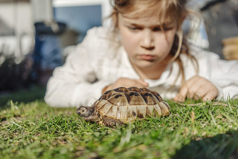 Girl looking at tortoise in garden - JOSF00897