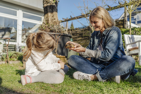 Smiling mature woman and girl with tortoise in garden stock photo