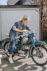 Happy woman on vintage motorcycle wearing a crown - JOSF00901