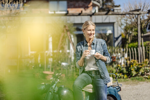 Lächelnde Frau auf altem Motorrad bei einer Kaffeepause - JOSF00906
