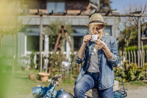 Frau auf Oldtimer-Motorrad genießt eine Kaffeepause - JOSF00907