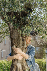 Woman in garden hugging a tree - JOSF00911