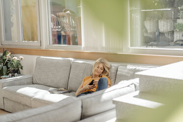 Woman at home on couch using cell phone - JOSF00913