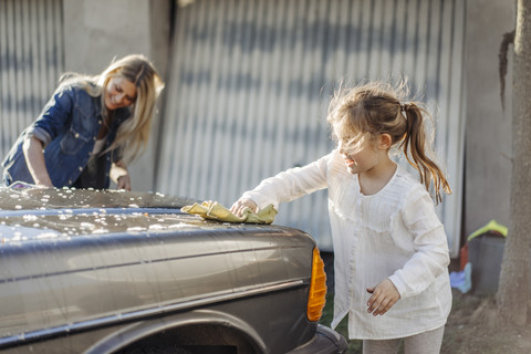 Reife Frau und Mädchen reinigen gemeinsam Auto, lizenzfreies Stockfoto