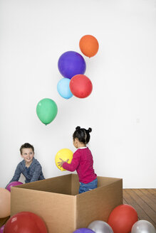 Zwei Kinder spielen mit Luftballon und Pappkarton - PSTF00024