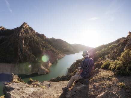 Spain, Gueejar Sierra, back view of hiker looking at Genil River at evening sunlight - LAF01841