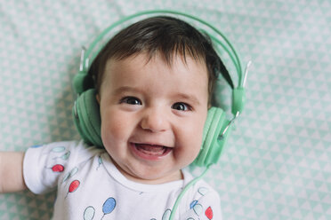 Porträt eines lachenden kleinen Mädchens mit Kopfhörern - GEMF01612