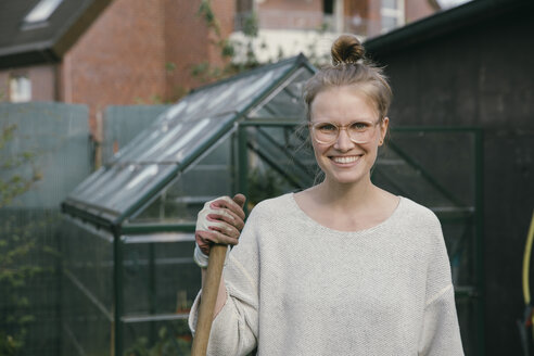Portrait of smiling young woman in front of greenhouse - MFF03491