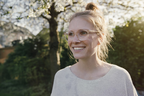 Porträt einer glücklichen blonden Frau im Garten, lizenzfreies Stockfoto