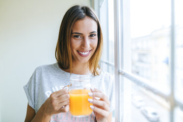 Porträt einer lächelnden jungen Frau mit einem Glas Orangensaft - KIJF01476