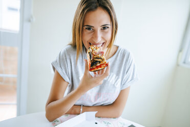 Porträt einer jungen Frau, die zu Hause eine Pizza isst - KIJF01478