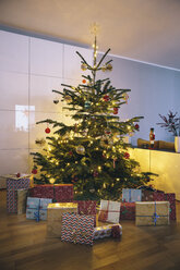 Geschmückter Weihnachtsbaum im Wohnzimmer mit Weihnachtsgeschenken im Vordergrund - MFF03505