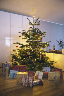Geschmückter Weihnachtsbaum im Wohnzimmer mit Weihnachtsgeschenken im Vordergrund - MFF03505