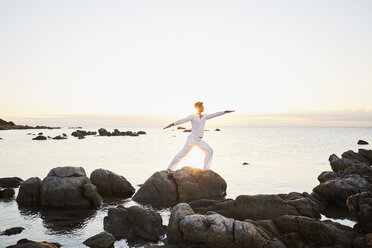 Älterer Mann macht Yoga-Übungen auf einem Felsen am Meer - PDF01237