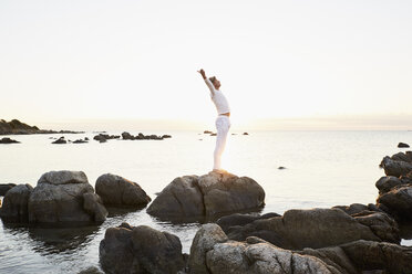 Älterer Mann macht Yoga-Übungen auf einem Felsen am Meer - PDF01238