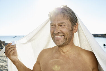 Porträt eines lächelnden Mannes mit Handtuch vor dem Meer - PDF01256