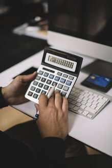 Man using calculator at desk, partial view - JPF00194