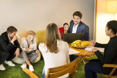 Geschäftsleute bei einem zwanglosen Treffen im Büro, lizenzfreies Stockfoto
