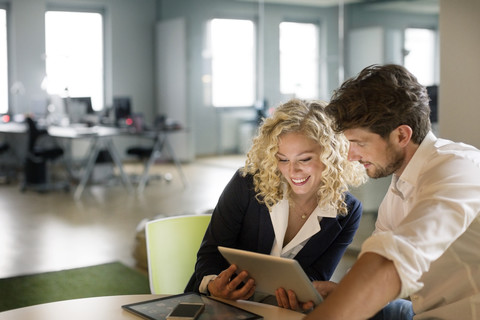 Geschäftsmann und Frau besprechen ein Projekt im Büro und benutzen ein digitales Tablet, lizenzfreies Stockfoto