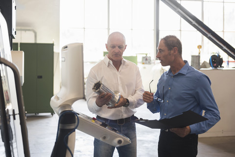 Two men examining product in factory stock photo