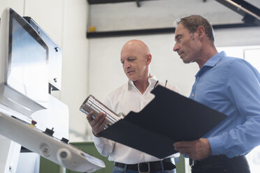 Zwei Männer begutachten ein Produkt in einer Fabrik - DIGF02453