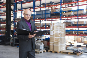 Businessman with documents on factory shop floor - DIGF02470