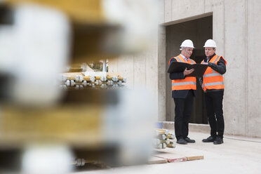 Zwei Männer mit Sicherheitswesten unterhalten sich auf einer Baustelle - DIGF02505