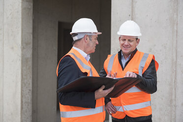 Two men wearing safety vests talking on construction site - DIGF02507