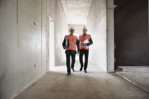 Zwei Männer mit Sicherheitsschuhen in einem im Bau befindlichen Gebäude, lizenzfreies Stockfoto
