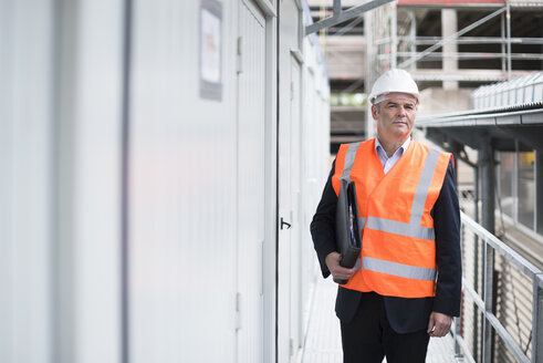 Mann mit Dokumenten und Sicherheitsweste auf einer Baustelle - DIGF02544