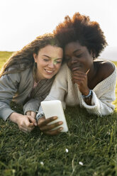 Two best friends lying in grass with cell phone - MGOF03341