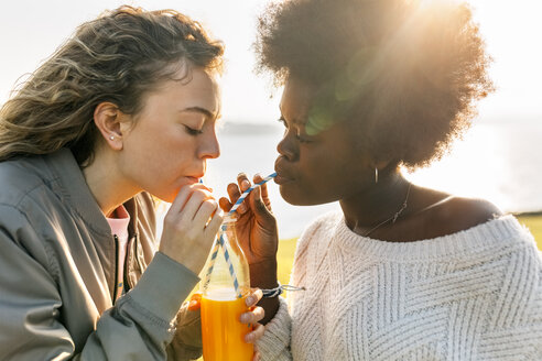 Zwei beste Freunde trinken Orangensaft im Freien - MGOF03360