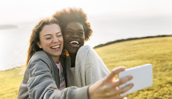 Zwei glückliche beste Freunde machen ein Selfie an der Küste - MGOF03362