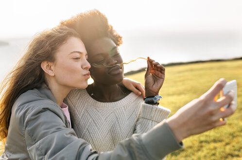 Zwei glückliche beste Freunde machen ein Selfie an der Küste - MGOF03363