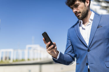 Young businessman looking at smartphone outdoors - GIOF02568