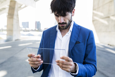 Young businessman holding futuristic portable device - GIOF02594