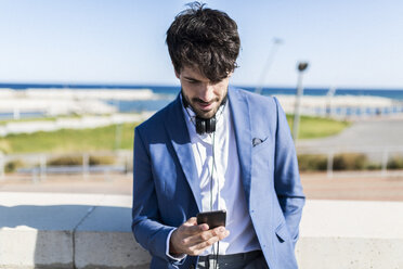 Young businessman looking at smartphone outdoors - GIOF02601