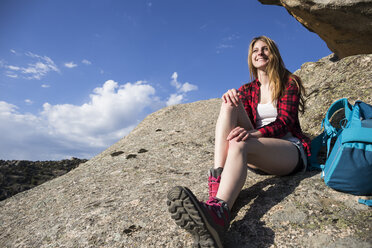 Spanien, Madrid, lächelnde junge Frau, die sich während eines Wandertages auf einem Felsen ausruht - ABZF02001